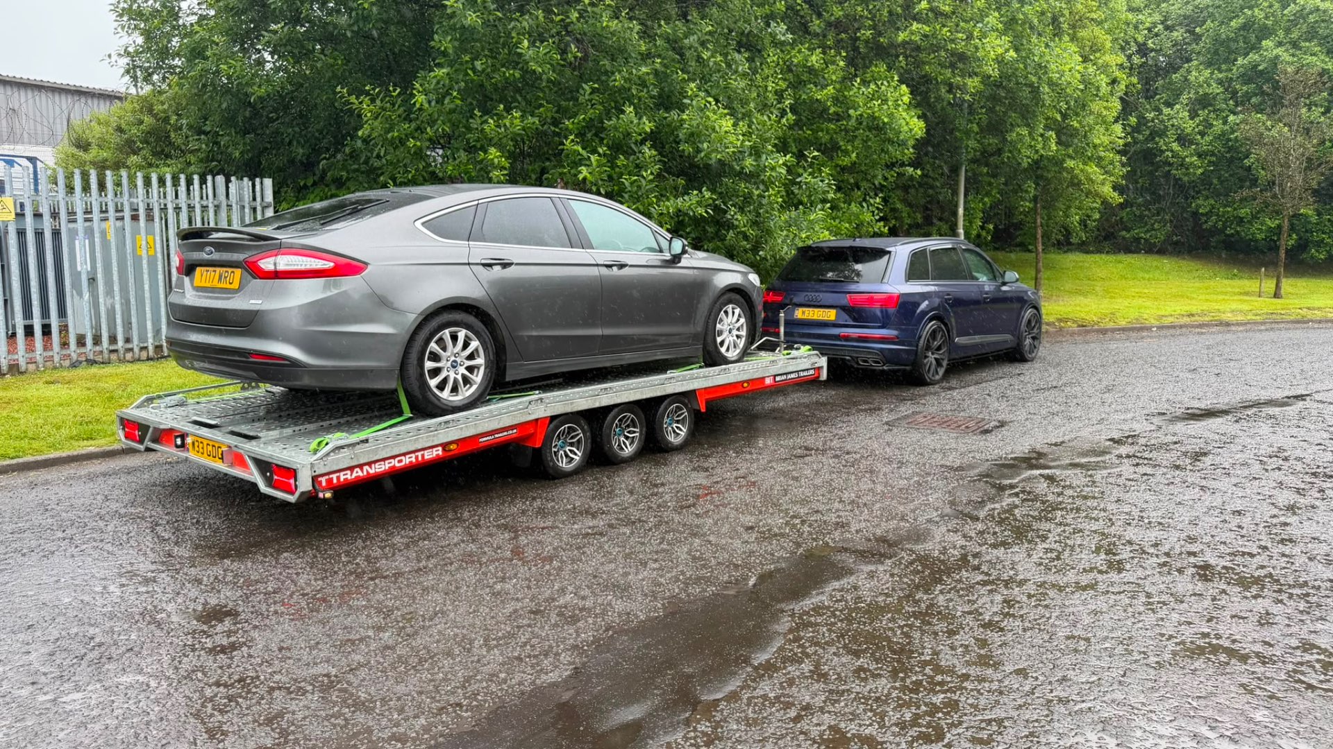 Ford Mondeo on covered transporter towed by Audi SQ7 in the rain