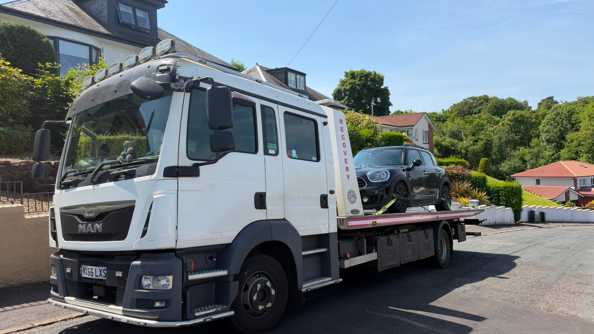 MAN 24-hour recovery truck delivering Mini Countryman in coastal town