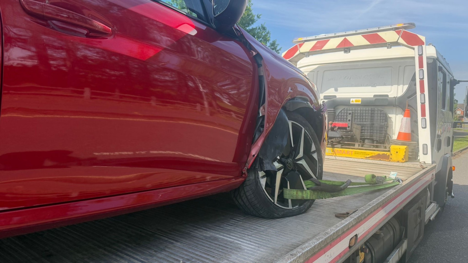 Accident-damaged red Peugeot on recovery flatbed