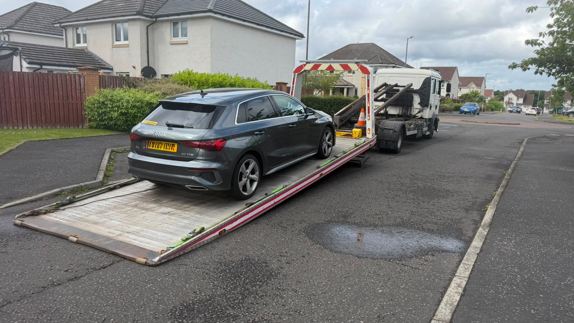 Grey Audi A3 Sportback loaded on MZL flatbed on residential street