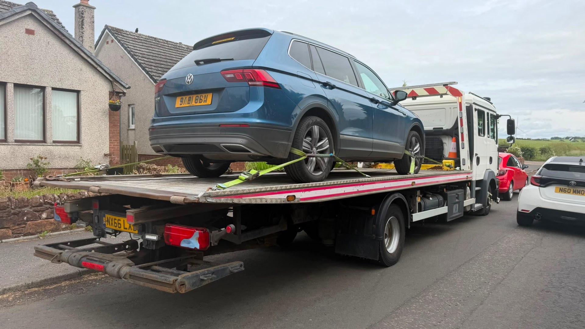 Blue VW Tiguan Allspace loaded on MZL recovery flatbed in village street