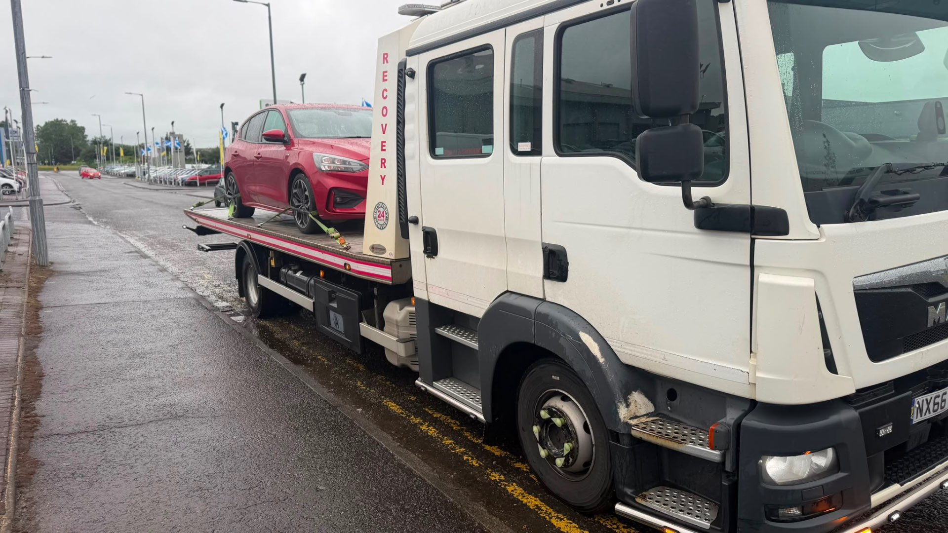 MAN recovery truck delivering red Ford Focus to Arnold Clark dealership