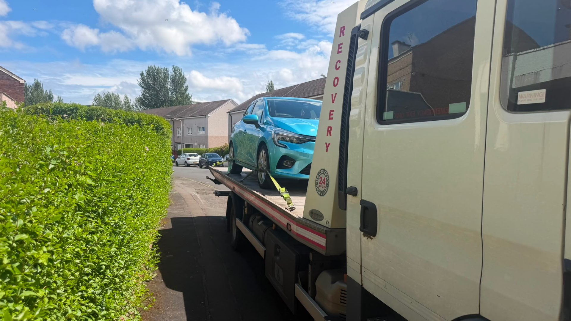 Blue Renault Clio loaded on MZL recovery flatbed in a residential street