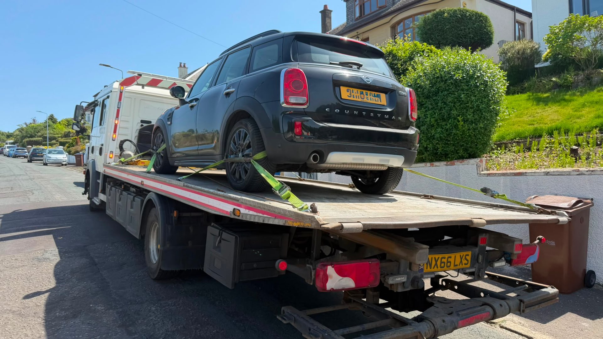 Black Mini Countryman secured on MZL recovery flatbed on residential hill